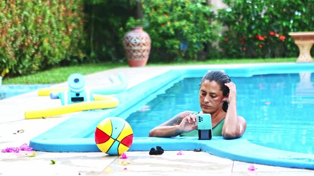 Woman listening to music on waterproof speaker in swimming pool