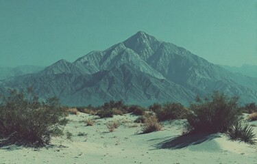 Barren landscape featuring a large mountain with arid foliage in the foreground under a teal sky