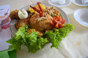 Indonesian fried rice with spices such as onions, chilies, and tomatoes, with various garnishes such as cucumber