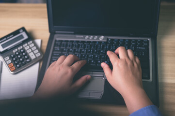 Hands typing on laptop keyboard with calculator and notepad for business, Office tasks, Online...