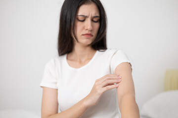 A young woman has skin irritation from dust allergies and itches on her arms.