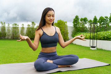 Beautiful confident asian woman practices yoga  in green park relax in nature. Portrait Asian girl do serene sincere peaceful in morning park sportswoman wellness health
