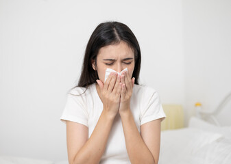 A young woman who uses a tissue to cover her mouth while sneezing and coughing has an allergic...