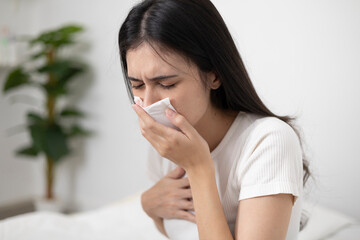 A young woman who uses a tissue to cover her mouth while sneezing and coughing has an allergic...