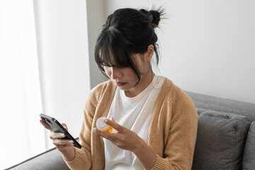 Asian woman Search for information on Internet in smartphone with holding bottled drug. girl reading information online on mobile phone medicine healthcare product concept