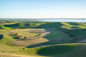 Naklejka premium High angle view of rural rolling landscape by the lake against blue sky, Red Rock, Victoria, Australia