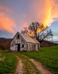 Obraz premium Rustic barn at sunset, dramatic sky