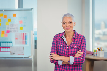 Senior woman standing at office before whiteboard with charts and desk with colored pencils