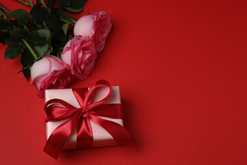 Pink rose with gift on red background
