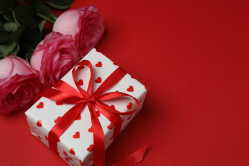Pink rose with gift on red background
