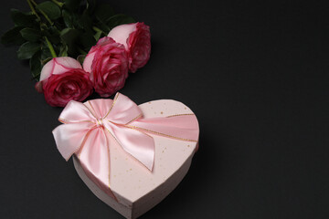 Pink rose with gift on black background
