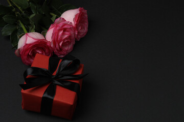 Pink rose with gift on black background
