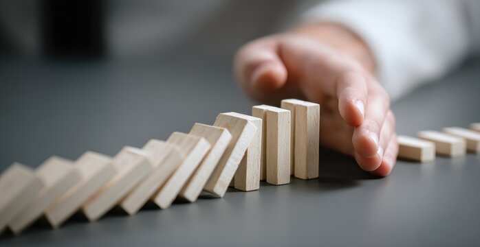 Hand stopping a row of dominoes