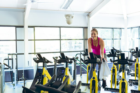 Fototapeta Black-and-yellow stationary spin bikes are lining up in rows under grid windows in studio