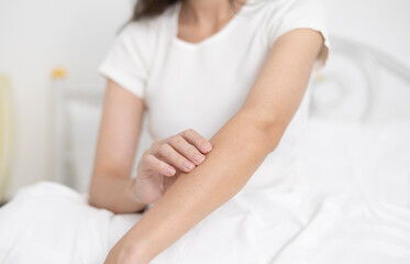 A young woman has skin irritation from dust allergies and itches on her arms.