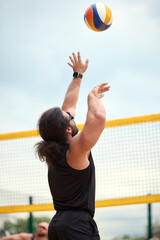 Man playing outdoor volleyball in summer with intense focus on the ball