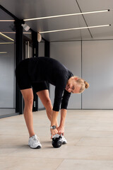 Woman practicing kettlebell lifting in a modern gym setting