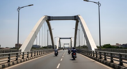 Motorcyclists traverse a modern, elegant arched bridge under a clear sky.