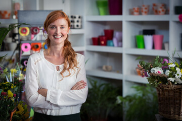 Florist standing inside floral shop, showcasing white shelves with colorful pots and ribbon spools