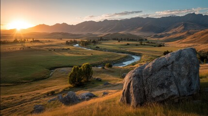 A scenic valley at sunset with a winding river, large rocks, green fields, and distant mountains under a peaceful sky