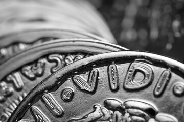 Close up view of silver color toy fake dollar plastic coins in monochrome.