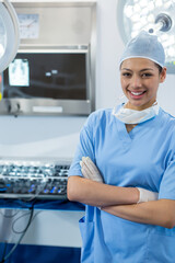 Obraz premium Female surgical nurse wearing scrubs and cap standing in operating room with tray, copy space