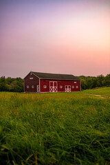 country landscape of a red barn in a grassy field at sunset © Christopher
