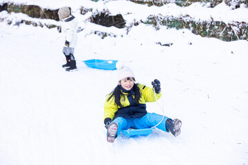 そりで斜面を滑る子供