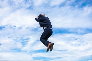 青空にジャンプするビジネスマン