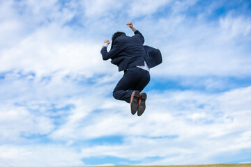 青空にジャンプするビジネスマン