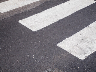 Close up view of a white painted pedestrian crossing on a dark asphalt road surface indicating...