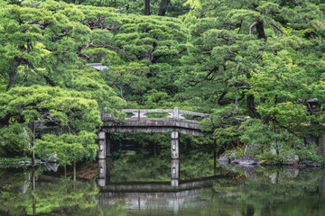 Historic stone bridge crosses a pond in a magnificent Japanese garden (Gonaitei). Kyoto Imperial palace, Japan.