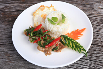 Pad kra pao moo (stir-fried thai basil with pork) and fried egg on old wood scene