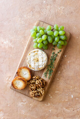 Baked brie cheese with grapes, thyme, baguette and nuts. French cuisine. Vegetarian food.