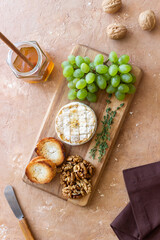Baked brie cheese with grapes, thyme, baguette and nuts. French cuisine. Vegetarian food.