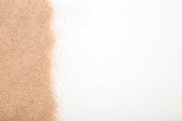 Dry light brown sea sand on white table background. Closeup. Empty place for text. Top down view.