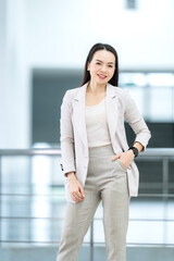 Modern businesswoman in beige suit smiling at camera in office, symbolizing success, ambition, and...