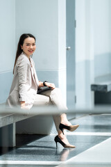 Smiling Asian businesswoman in beige suit sitting with tablet, symbolizing modern lifestyle,...