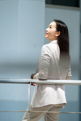 Asian businesswoman in beige suit smiling confidently with modern style, symbolizing empowerment,...