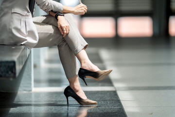 Close-up of stylish businesswoman holding pen while sitting in heels, symbolizing leadership,...