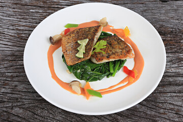 Sea bass steak served with salad greens dressed with olive oil and lemon slices