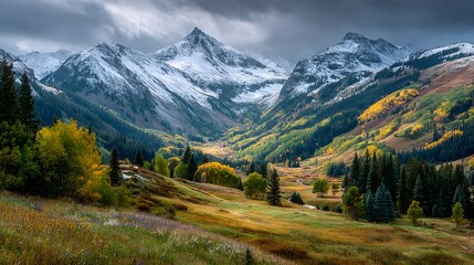 Obraz premium Dramatic clouds emerging over snow capped peaks and autumn foliage in colorado valley