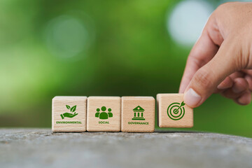 ESG target Environmental, Social, and Governance, representing sustainable business strategy and corporate responsibility, iso environmental. Hand placing a wooden block with ESG icon.