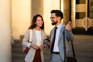 Businesspeople walking and talking outdoors, waving at someone