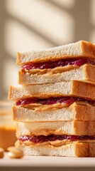 Stack of classic peanut butter and jelly sandwiches with soft bread in warm natural light, ideal for food, snack, or lunch concepts.