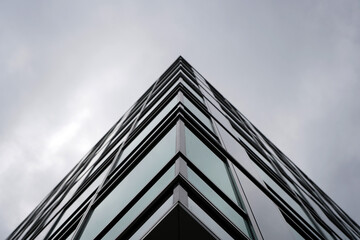 Modern glass building corner captured from low angle, emphasizing sharp lines, minimalism, and...