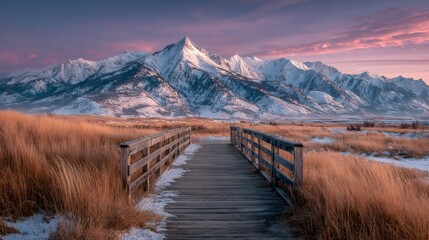 Wooden bridge leading to majestic snow capped mountains at dawn