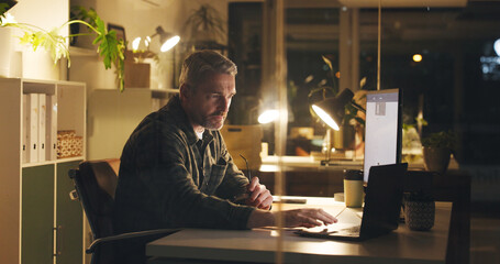 Man, reading and laptop at night in office with review, work article and deadline. Mature person,...