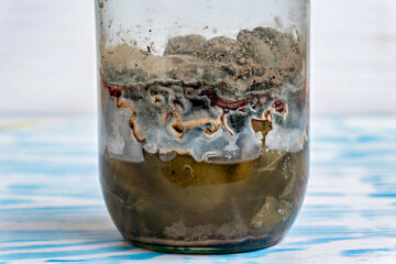A glass jar filled with a substance that appears to be a mixture of dirt sand and possibly some organic matter