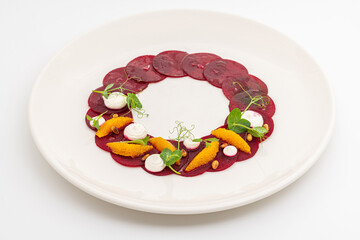 Beet carpaccio with orange slices, fresh greens and cream dots